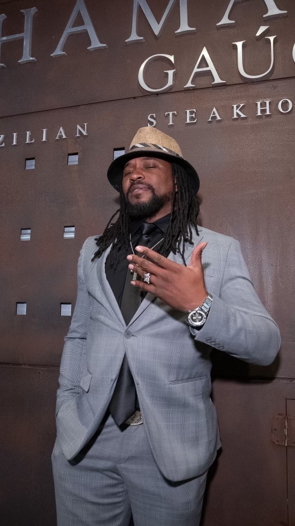 THA PARTY KING in a grey suit and hat on a step-and-repeat wall